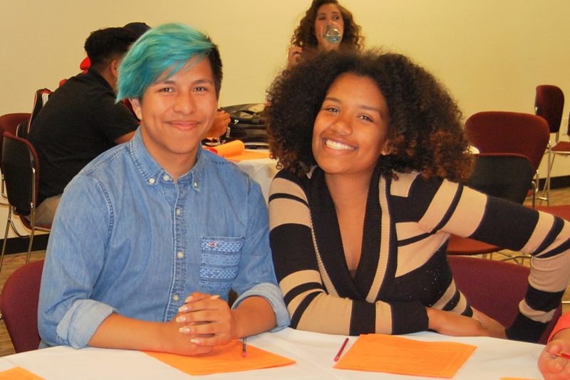 Two students sitting and smiling at the camera